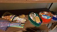 Photo showing colorful knitting needles, beads in a canister, and button cards on wooden shelf