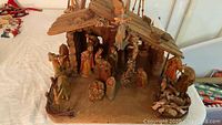 Full view of the nativity scene showing wooden manger and multiple figures inside and around it.