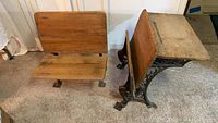 Photo showing full view of antique wooden school desk and matching bench on carpeted floor.
