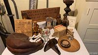 Overview of assorted vintage German collectibles including wooden items, glassware, metal tins, and figurines arranged on a surface in a basement area.