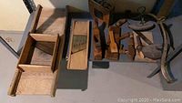 Photo showing wooden hand planes, washboard, and other antique wooden hand tools arranged on a surface.