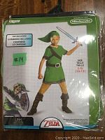 Front of the unopened costume package showing a child model wearing the Link costume with sword and hat. Size marked L (10-12).