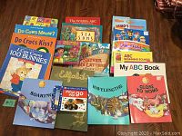 Photo of 16 children's educational books with colorful covers, showing titles about alphabet, numbers, rhymes, and animals.