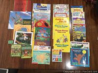 Photo showing a collection of 26 soft cover children's books assorted on a wooden table