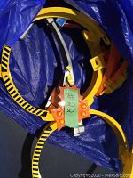 Blue bag containing coiled orange Hot Wheels track loop pieces with black stripes.