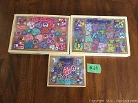 Three Melissa and Doug wooden bead sets in wooden trays with purple string, including heart, butterfly, and flower shaped beads, used condition.