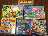 Six boxed children's board games arranged on floor: Mouse Trap, Pie Face, Peppa Pig Surprise Slides, Let's Go Fishin', Spuzzle Frozen edition, and Sorry!