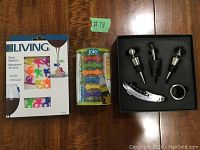 Photo shows boxed colorful silicone glass markers, plastic container of silicone bottle markers, and wine accessory set in foam: three bottle stoppers, corkscrew and drip collar.