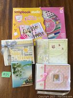 Photo showing the scrapbook software kit box with CD and four albums including baby keepsake book and floral photo album