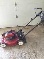 Side angle showing the red deck and side engine cover, rear wheels, and handlebar controls