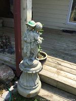 Front view of cement fountain showing fluted pedestal and two children statues