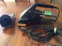 Photo showing side view of Hoover handheld vacuum with cord and detachable dust bag on wooden table