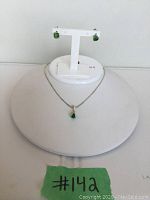 Green teardrop pendant necklace with matching green stud earrings displayed