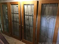 Four hardwood-framed pieces (two doors flanked by two side panels) leaning against wall
