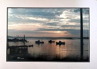 Photo of the original photographic print showing waterfront with boats at sunset with signature and date.