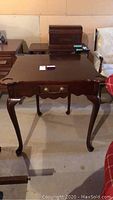 Front view of vintage square wooden table with drawer and cabriole legs.