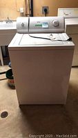 Kenmore white top load washing machine with control panel and lid, front view.