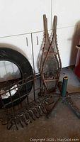 Photo of vintage wooden snowshoes with rawhide webbing beside tire