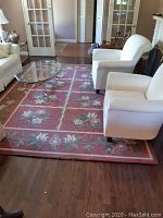 Full view of the Mingani Collection area rug 8x11 laid in a living room under chairs and glass coffee table, showing floral pattern and border.