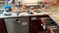 Countertop with various kitchen gadgets, glassware, cutting boards, and utensils arranged