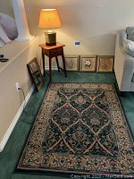 Side table with lamp, wall art, mirror, and rug in corner of room