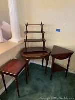 Set of three small dark wood side tables and a dark wood tiered wall display unit against a wall.