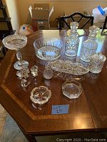 Top view of table with all 12 cut crystal pieces including decanters, bowls, animals, and other items arranged in groups.