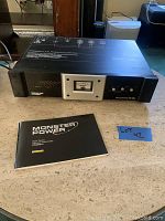 Front angle of Monster Power HTS 3500 Home Theater Reference Power Center with accompanying user manual on table.