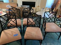 Front view of five black Asian style dining chairs with latticed backs and tan upholstered seats showing some stains.