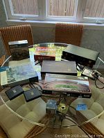 Full view of seven assorted games and puzzles on glass table including puzzles, Yahtzee games, and metal cubes