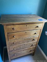 Front view of wooden dresser showing five drawers with round wooden knobs and keyhole details.