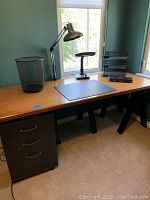 Full view of wood office desk with black metal legs and file cabinet underneath, plus desk accessories on top.
