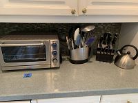 Full view of countertop with toaster oven, utensil holder, knife set, and tea kettle