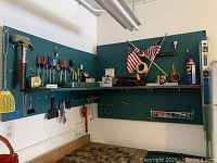 Image of tools mounted on blue pegboard including hammer, screwdrivers, tape measure, wrenches, toolbox, and miscellaneous items
