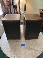 Pair of Canton Karat 200 speakers shown with wood veneer sides and black metal mesh front grilles.