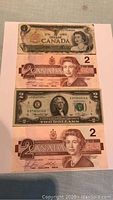 All four banknotes stacked slightly offset showing front faces of Canadian and US bills.
