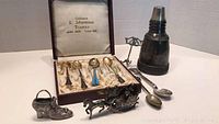 Overall view of the lot including spoons in case, horse and sleigh figurine, shaker, and shot glass.