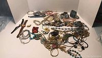 Full view of assorted bracelets, watches, necklaces, and costume jewelry on white background.