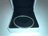 Silver-tone Pandora bangle bracelet inside a black velvet lined white Pandora box, clearly showing the crystals on the bracelet.