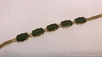 Close-up photo of the bracelet showing green jade stones and gold plating detail.