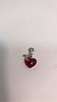Front view of the red heart-shaped Swarovski crystal charm pendant with the silver-tone loop and decorative twist.