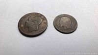 Photo of two coins, one larger worn Napoleon III coin dated 1855 and smaller Italian coin showing profile portrait.