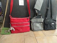 Four purses arranged against a black backdrop showing red, green, gray, and black colors and various zippered compartments.