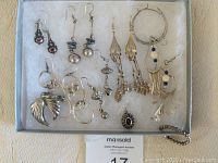 Full collection of silver earrings in a box, displaying variety of sizes and designs from the lot.