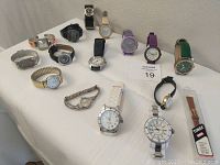 Wide view of all 15 watches laid out on a white surface showing variety in styles and bands.