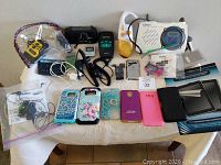 Full view of lot showing iPod, cases, digital devices, weather band radio, cables and small accessories.