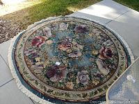 Full view of the large round area rug showing floral pattern, border and fringe.