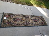 Full view of the floral floor runner rug laid out flat on concrete showing its full length and pattern.