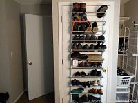 Full view of 15 pairs of ladies shoes and boots on hanging rack on door and floor rack, showing a mix of styles and colors.