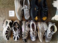 Top-down view showing various pairs of ladies shoes in black, white, metallic silver, and beige Sorel snow boots, all size 8.